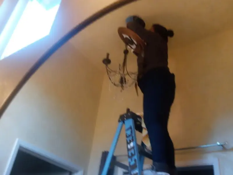Electrician installing a chandelier in a Ballenger Creek residence